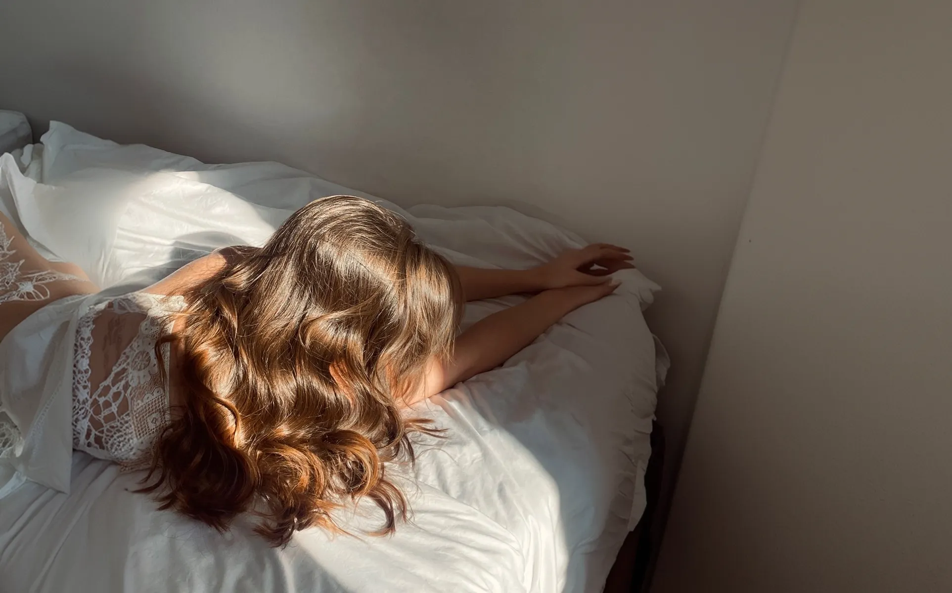 Woman with healthy wavy hair on a bed in natural morning light